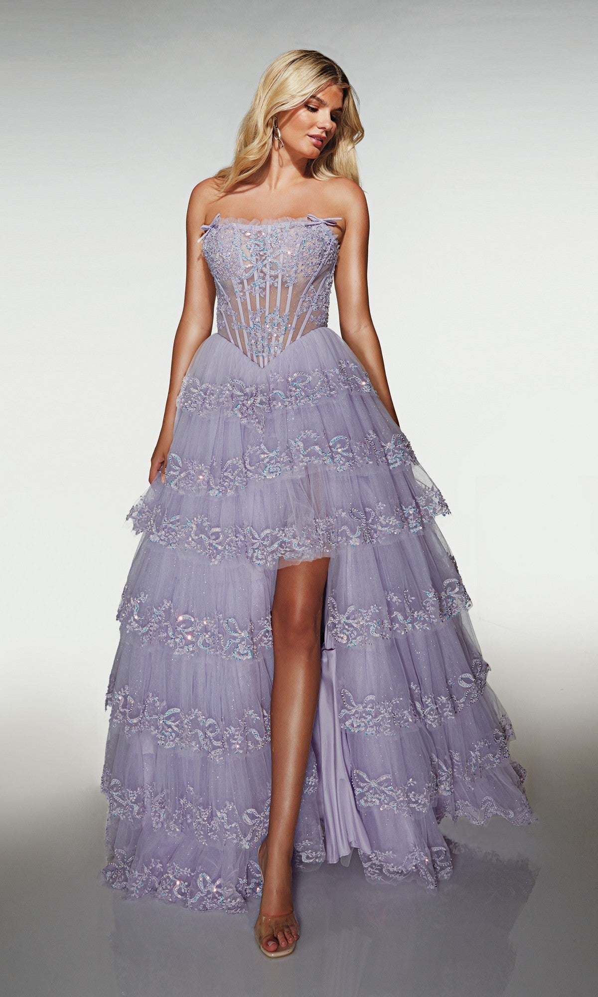 A woman poses in the Alyce 62191 lilac long prom dress with a strapless sheer corset bodice, floral lace, tulle a-line skirt, high slit, and strappy heels.
